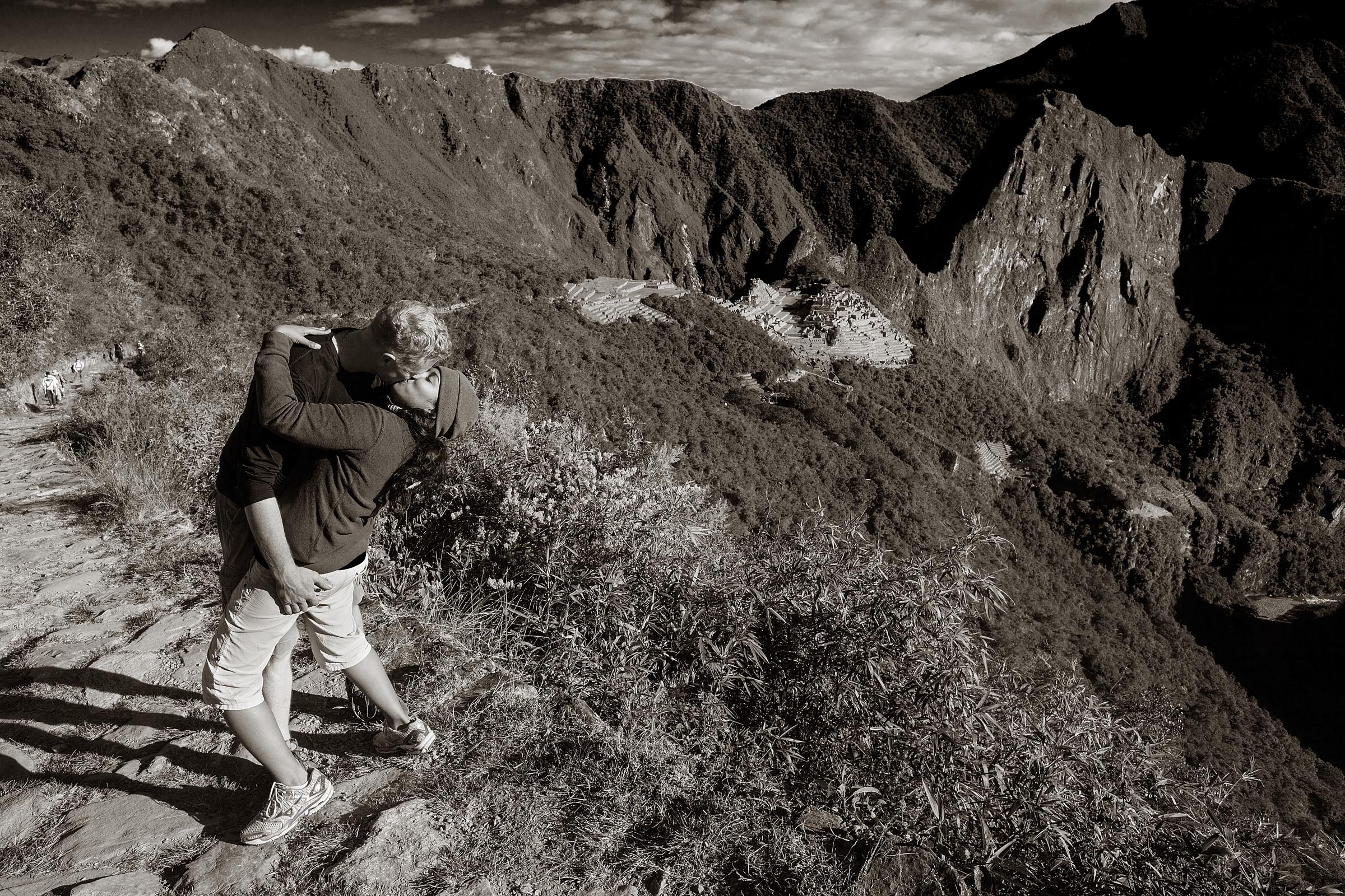 A young couple embrace in a kiss celebrating their arrival to Machu Picchu.