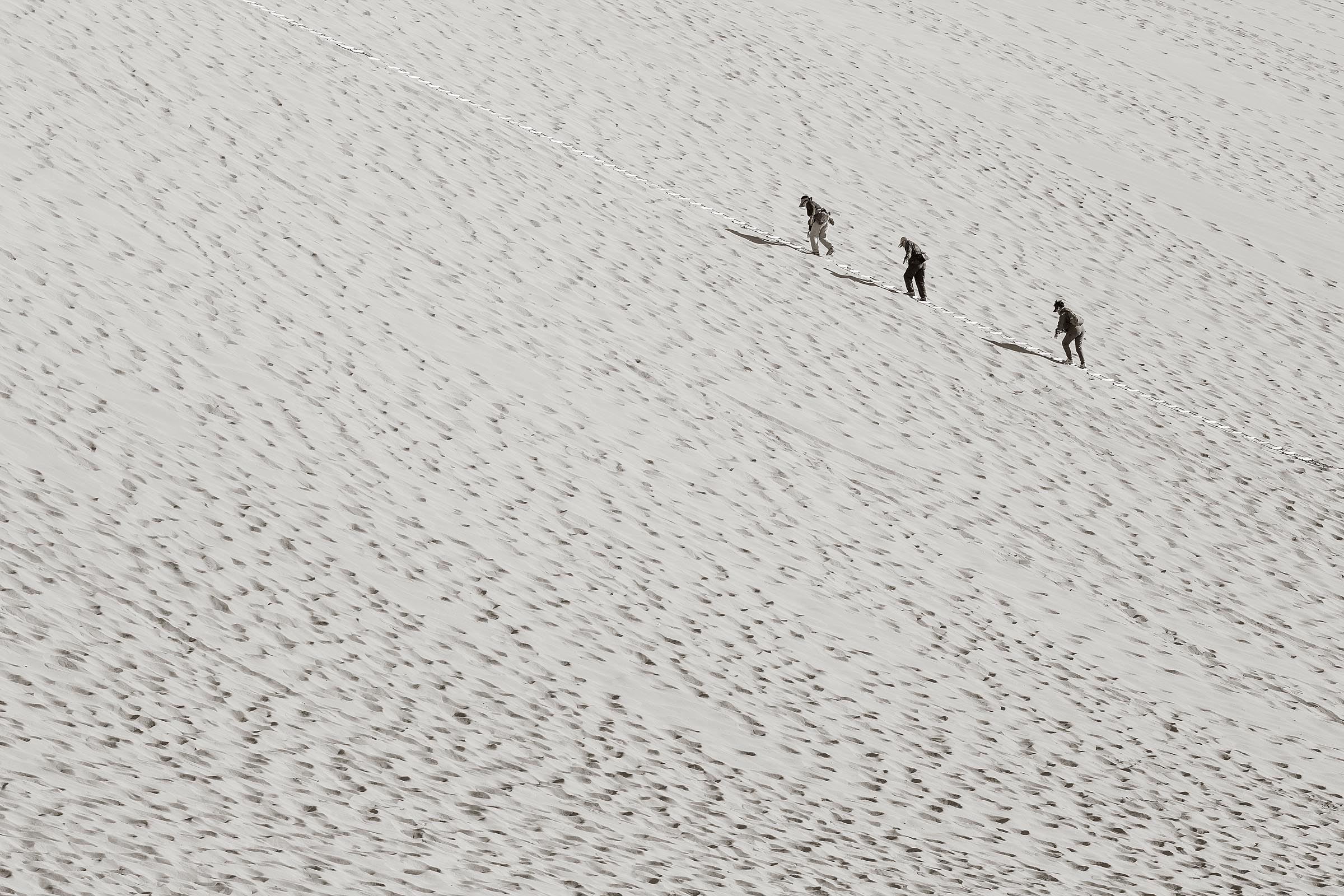 Visitors to the Dunhuan sand dunes struggle up the mountain of sand.