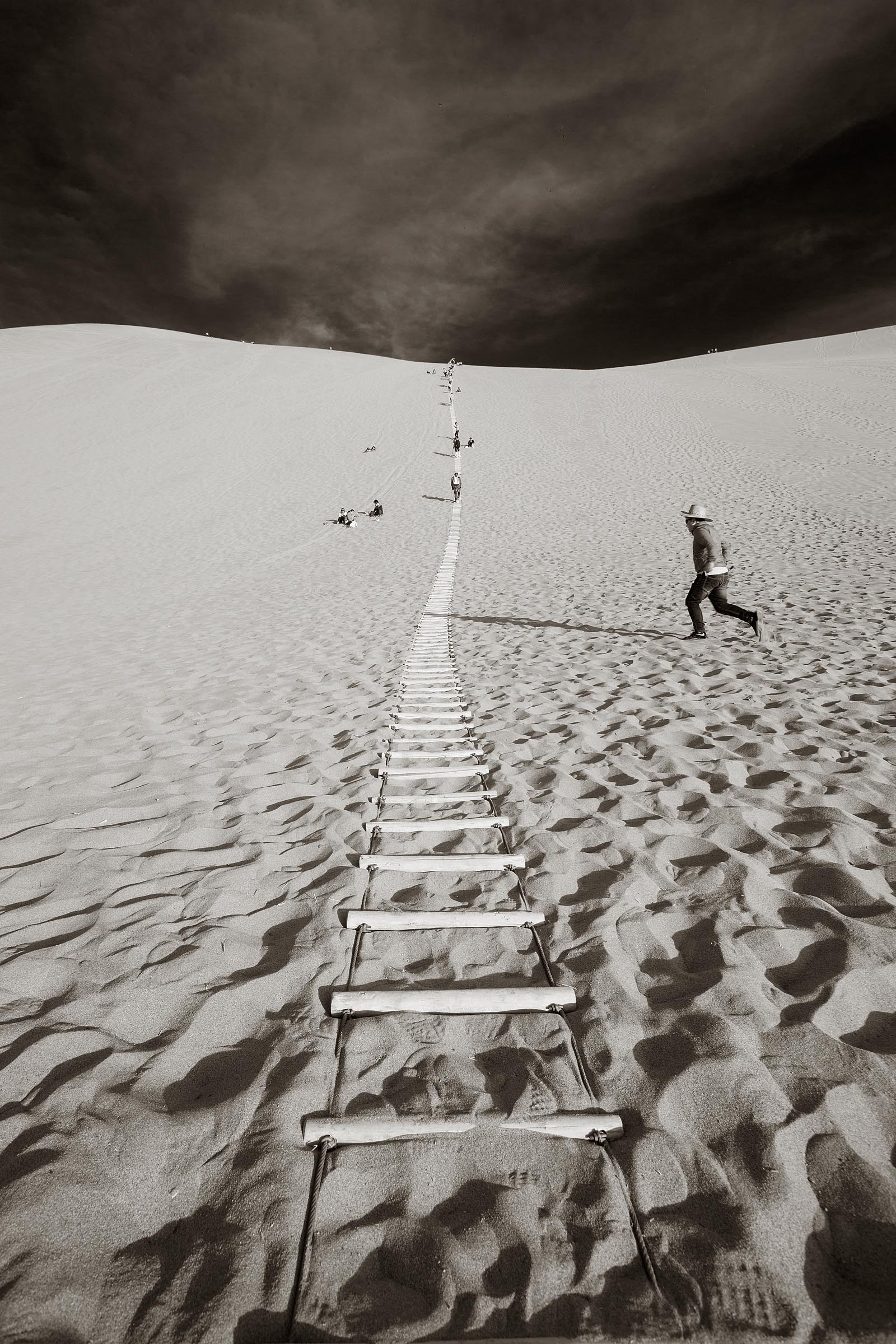 A ladder in the sand helps visitors to climb the tall sand dunes at Dunhuan.